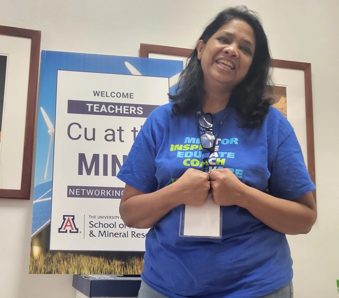 smiling teacher in front of sign